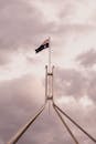 The Australian flag flying high over Parliament House in Canberra with a dramatic cloudy sky background.